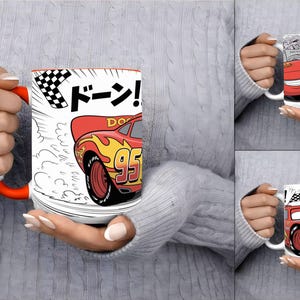 K&ouml;nnte beinhalten: Ein wei&szlig;er Keramikbecher mit orangefarbenem Henkel, der ein rotes Rennauto mit gelben Flammen und der Nummer 95 zeigt. Das Design umfasst eine Zielflagge, Bewegungslinien und den japanischen Schriftzug "Doon!" in fetten schwarzen Buchstaben.