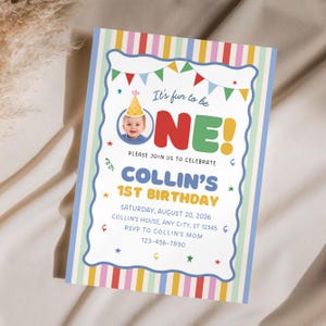 May include: A rectangular birthday invitation card featuring a colorful vertical striped border. The center displays the text 'It's fun to be ONE!', a photo of a baby in a party hat, and event details for Collin's 1st birthday on August 20, 2026.