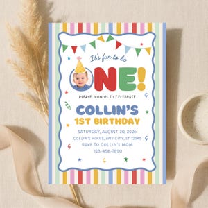 May include: A rectangular birthday invitation card featuring a colorful vertical striped border and a white center. The text reads It's fun to be ONE! COLLIN'S 1ST BIRTHDAY, with details for Saturday, August 20, 2026, and a photo of a baby in a party hat.