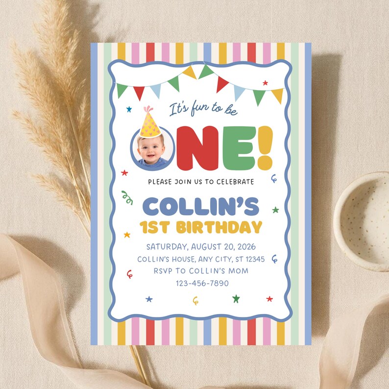 May include: A rectangular birthday invitation card featuring a colorful vertical striped border and a white center. The text reads It's fun to be ONE! COLLIN'S 1ST BIRTHDAY, with details for Saturday, August 20, 2026, and a photo of a baby in a party hat.