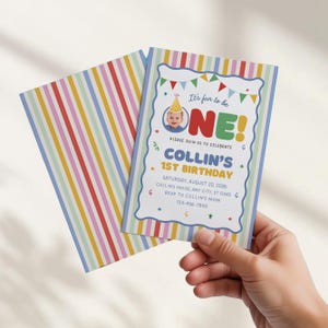 May include: A rectangular birthday invitation card featuring a colorful vertical striped pattern on the back and a white front with a scalloped blue border. The text reads: It's fun to be ONE! COLLIN'S 1ST BIRTHDAY, AUGUST 20, 2026, with party details.