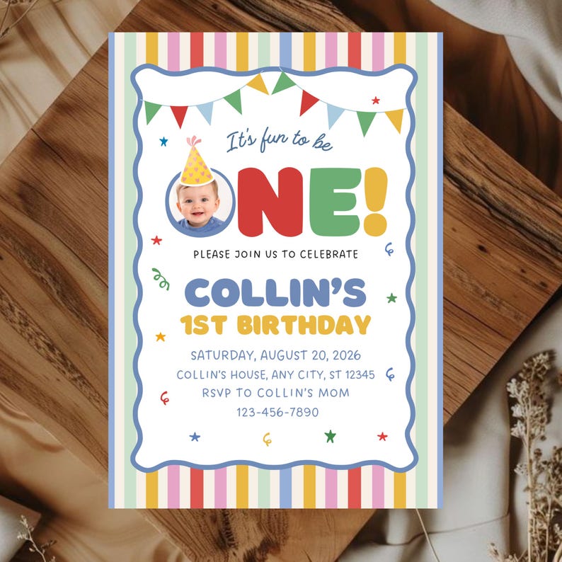 May include: A rectangular birthday invitation card featuring a colorful striped border and a scalloped white center. The text reads: It's fun to be ONE! PLEASE JOIN US TO CELEBRATE COLLIN'S 1ST BIRTHDAY SATURDAY, AUGUST 20, 2026 COLLIN'S HOUSE, ANY CITY, ST 12345 RSVP TO COLLIN'S MOM 123-456-7890.