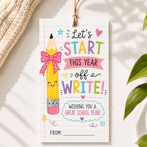 Pode incluir: Uma etiqueta de presente retangular com fundo de papel pautado branco e uma ilustração de um lápis amarelo com um laço rosa de bolinhas. O texto diz: Let's START THIS YEAR off WRITE! WISHING YOU A GREAT SCHOOL YEAR! FROM: com estrelas e corações coloridos.