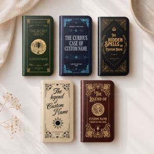 Puede incluir: Una variedad de fundas para teléfonos con forma de libro con varios títulos y diseños. Las fundas presentan títulos como "The Secret Life Of", "The Curious Case Of" y "The Hidden Spells Of". Cada funda tiene un esquema de color único y elementos decorativos.