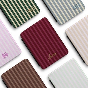 May include: A collection of personalized phone cases with vertical stripe patterns in various colors, including green, pink, brown, and burgundy. Each case features a name or initials in a contrasting color.