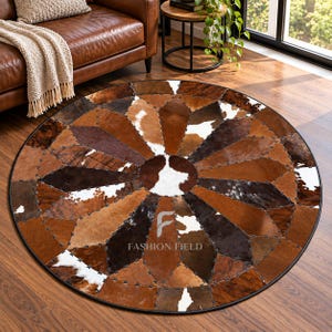May include: A round area rug constructed from stitched panels of cowhide in various shades of brown, tan, and white. The rug features a geometric starburst pattern radiating from a central circular patch, with the text FASHION FIELD printed in white.