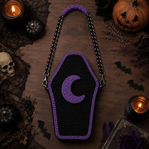 May include: A coffin-shaped crochet bag in black with a purple border and a purple crescent moon appliqué. The bag features a black metal chain strap with a purple crochet handle cover, attached to the top corners with black metal lobster clasps.