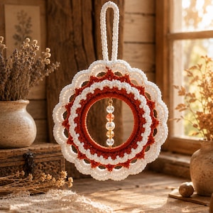 Pode incluir: Uma grinalda de crochê artesanal, em branco e vermelho enferrujado. A grinalda apresenta uma borda ondulada e um anel central adornado com contas penduradas. É suspensa por um laço branco, ideal para decoração sazonal.