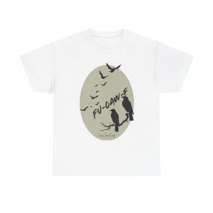 May include: White t-shirt with a graphic design featuring two black birds perched on a branch inside an oval shape. The text "FU-CAW-F" is above the birds, with smaller flying birds in the background. The shirt has a crew neck and short sleeves.