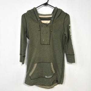May include: An olive green hooded pullover with three-quarter length sleeves, a double-breasted button placket, and a front kangaroo pocket. The garment features dark contrast stitching, a hood with drawstrings, and the text Hollister Co. on the pocket.