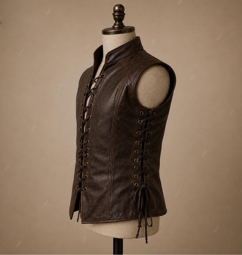 May include: A dark brown sleeveless vest featuring a high collar and a front lace-up closure with metal eyelets. The sides of the vest also include lace-up detailing with matching brown cords that tie at the bottom, creating a structured fit.
