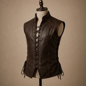 May include: A dark brown sleeveless vest featuring a high collar and a front center lace-up closure with brass-toned metal eyelets. The garment includes side lacing details with matching dark brown cords, finished with a textured, weathered surface.