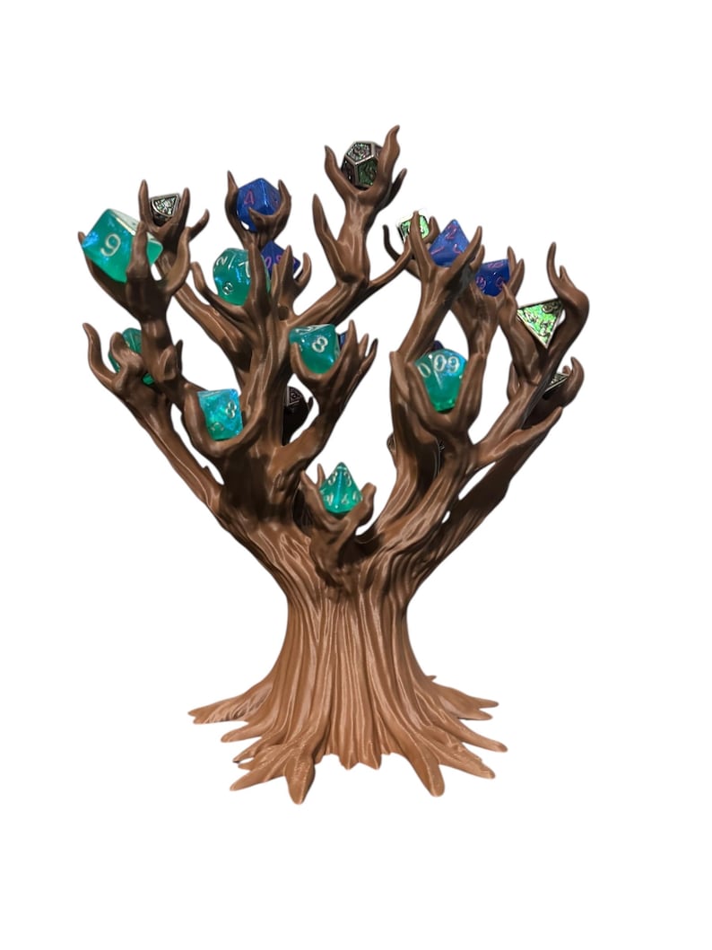 Puede incluir: Un soporte para dados en forma de &aacute;rbol marr&oacute;n con m&uacute;ltiples ramas, cada una sosteniendo un dado colorido. Los dados son de varios colores, incluyendo azul, verde y negro. El soporte est&aacute; hecho de un material texturizado, que se asemeja a la madera.