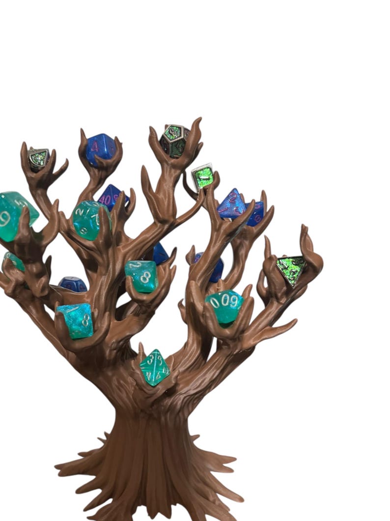 Puede incluir: Un soporte para dados en forma de &aacute;rbol marr&oacute;n con m&uacute;ltiples ramas, cada una de las cuales sostiene un dado de diferente color. Los dados son de varios colores, incluyendo azul, verde y transparente. El soporte est&aacute; dise&ntilde;ado para exhibir y guardar dados.