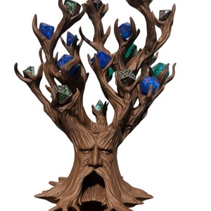 Puede incluir: Un soporte para dados en forma de &aacute;rbol marr&oacute;n, con una cara tallada en el tronco. Las ramas sostienen varios dados poli&eacute;dricos en tonos azules, verdes y plateados. La base es de color marr&oacute;n oscuro.