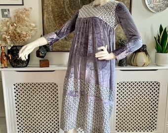 May include: A purple velvet dress with a white and blue floral print on the bodice and hem. The dress has long sleeves and a gathered waist.