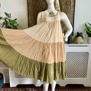 May include: A tiered maxi dress with a cream, light brown, and green color scheme. The dress has a sleeveless design and a gathered skirt.