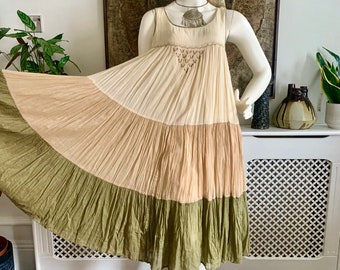 May include: A tiered maxi dress with a cream, light brown, and green color scheme. The dress has a sleeveless design and a gathered skirt.