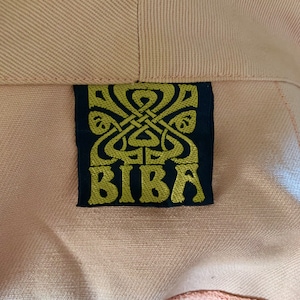 May include: A close-up of a black label with a gold design and the word "BIBa" in gold lettering.