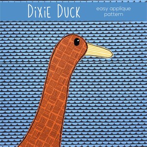 以下が含まれることがあります： 「Dixie Duck easy applique pattern」というタイトルの、黄色いクチバシを持つ、茶色とオレンジ色のアヒルの頭部のアップリケパターンです。