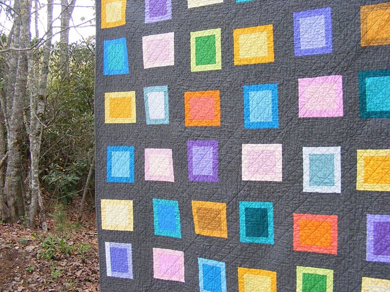 May include: A quilt with a gray background and a grid of colorful squares. The squares are in various shades of blue, green, yellow, orange, pink, and purple.