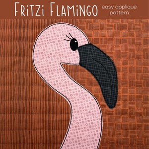 May include: A pink flamingo applique pattern with a black beak and eye, set against a brown background. The text "Fritzi Flamingo" and "easy applique pattern" are displayed at the top. The design is from "shiny + happy world".