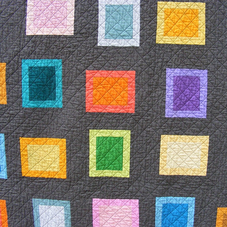May include: A quilt with a gray background and a grid of colorful squares. The squares are in various shades of pink, blue, green, orange, and purple.