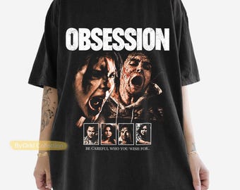 May include: A black short-sleeve t-shirt featuring a graphic print with the word OBSESSION in white text. The design includes two large faces with distressed expressions and four smaller portraits below, with the text BE CAREFUL WHO YOU WISH FOR.