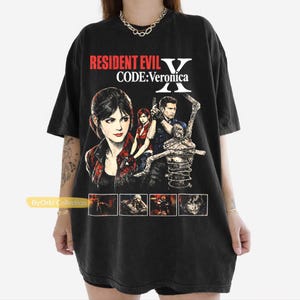 May include: Black t-shirt featuring a graphic from the video game Resident Evil Code: Veronica. The design includes characters and the game's title in red and white. The shirt has a crew neck and short sleeves.