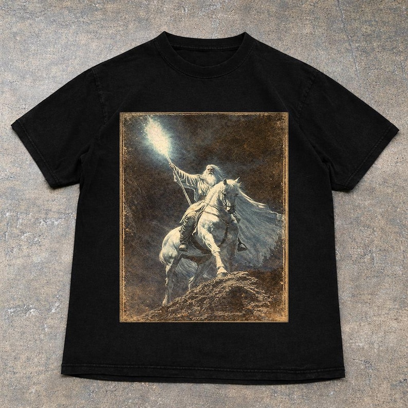 Black Vintage Gandalf on horseback with glowing staff in a vintage fantasy illustration, lord of the rings inspired wizard design, lotr fan art style graphic tee, magical wizard scene with detailed horse and mystical light, fantasy lover gift, wizard gift idea, lord of the ring shirt, gandalf shirt, fantasy aesthetic clothing, unisex streetwear tee, high quality print, perfect gift for lotr fans and magic lovers