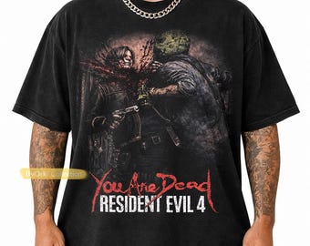 May include: Black graphic t-shirt featuring a violent scene from Resident Evil 4. The design includes the text "You Are Dead" and "Resident Evil 4" in red and white. The shirt has a vintage, distressed look.