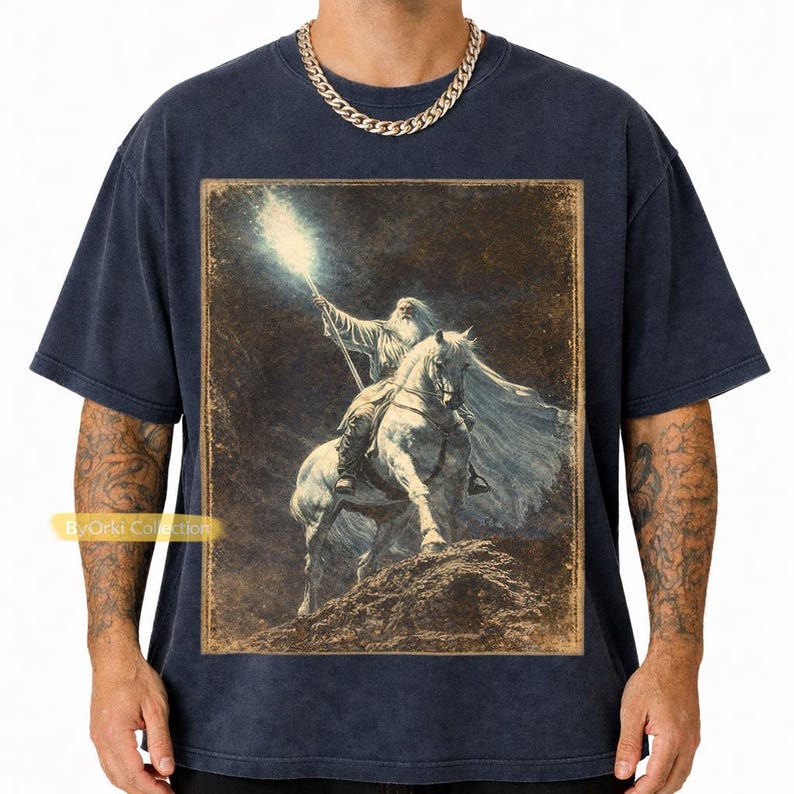 Navy Vintage Gandalf on horseback with glowing staff in a vintage fantasy illustration, lord of the rings inspired wizard design, lotr fan art style graphic tee, magical wizard scene with detailed horse and mystical light, fantasy lover gift, wizard gift idea, lord of the ring shirt, gandalf shirt, fantasy aesthetic clothing, unisex streetwear tee, high quality print, perfect gift for lotr fans and magic lovers