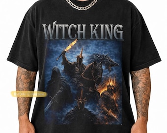 May include: A black short-sleeve t-shirt featuring the text WITCH KING in a silver font above a graphic illustration of dark armored figures on horseback with glowing swords against a dark blue and smoky background.