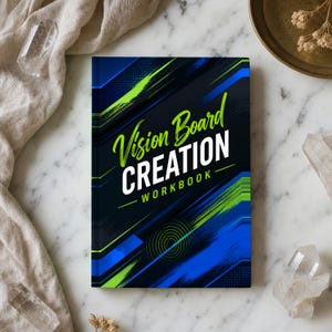 Op de afbeelding: Een rechthoekig werkboek met een donkerblauwe en zwarte kaft met felgroene diagonale penseelstreken en geometrische patronen. De tekst Vision Board CREATION WORKBOOK staat in het wit en groen op de voorkant gedrukt.