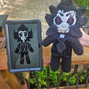 May include: A handmade crochet plush doll featuring a black and white color scheme with red eyes, a spiky hairstyle, and a formal suit outfit. Next to the plush is a tablet displaying a digital illustration of the same character design.