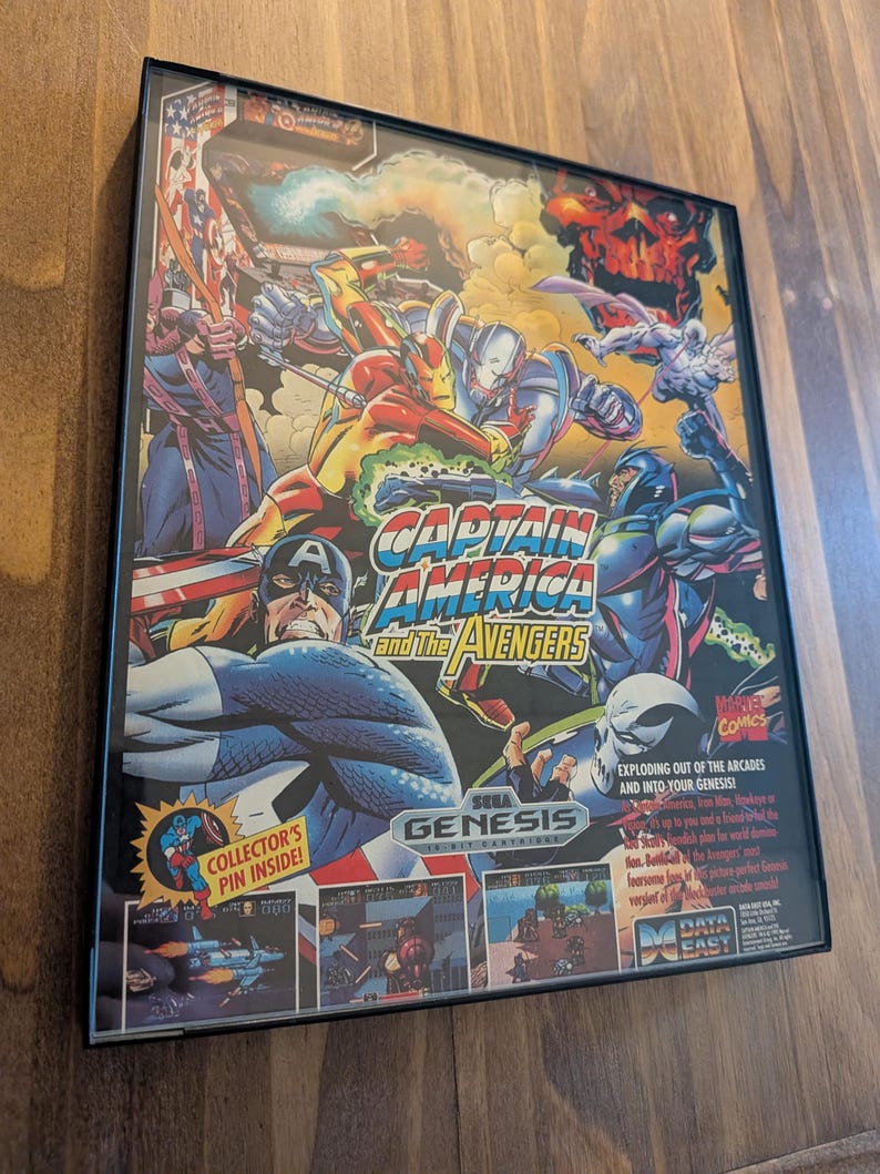 Puede incluir: Cartucho de juego Sega Genesis enmarcado para "Captain America and The Avengers". La car&aacute;tula presenta ilustraciones de estilo c&oacute;mic de Capit&aacute;n Am&eacute;rica, Iron Man y otros personajes de los Vengadores. El t&iacute;tulo del juego se muestra de forma destacada.
