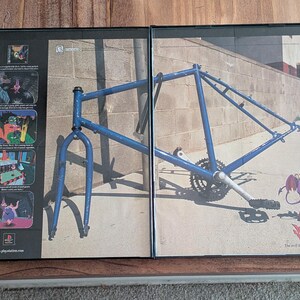 Peut inclure: Image encadrée d'un cadre de vélo bleu et d'un personnage de dessin animé. L'image est divisée en deux panneaux. Le panneau de droite montre le cadre du vélo, tandis que le panneau de gauche présente un personnage de dessin animé.