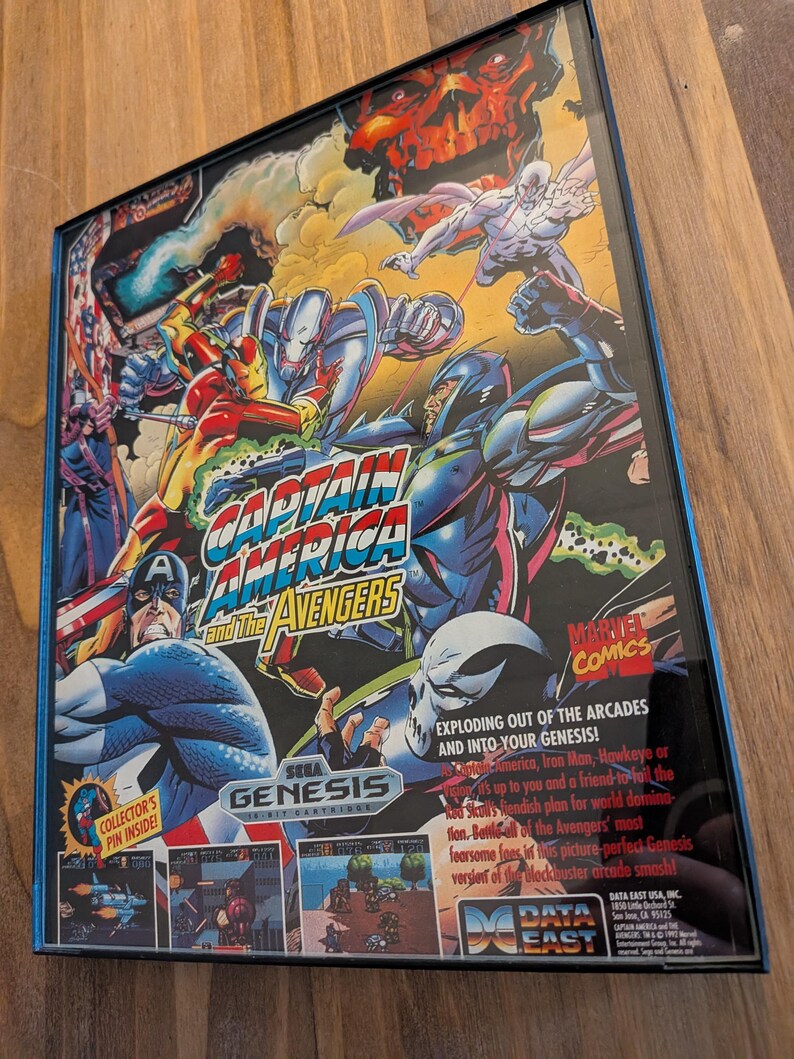 Puede incluir: Una caja de cartucho de juego de Sega Genesis para "Captain America and the Avengers". La caja presenta ilustraciones coloridas de estilo c&oacute;mic del equipo de los Vengadores, incluyendo al Capit&aacute;n Am&eacute;rica, Iron Man y Hawkeye. El logotipo de Marvel Comics es visible.