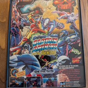 Puede incluir: Un cartucho de videojuego Sega Genesis enmarcado para "Captain America and The Avengers". La car&aacute;tula presenta a Capit&aacute;n Am&eacute;rica, Iron Man y otros personajes de Marvel en acci&oacute;n. El juego es un t&iacute;tulo de Marvel Comics.
