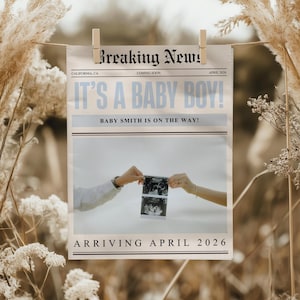 May include: A newspaper-style announcement, held by a wooden clip, reveals the text "Breaking News!" and "It's a Baby Boy!" in blue. The announcement includes the text "Baby Smith is on the way!" and "Arriving April 2026."