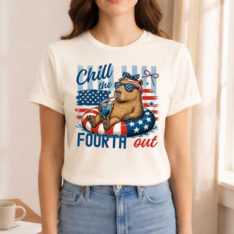 May include: Cream-colored t-shirt featuring a capybara wearing sunglasses and a patriotic headband, relaxing on a red, white, and blue inner tube. The shirt has the text "Chill the Fourth out" in blue and red.