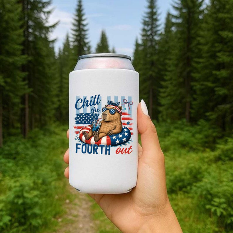 May include: White can cooler featuring a capybara wearing sunglasses and a patriotic headband, floating on a red, white, and blue inner tube. The text "Chill the Fourth out" is displayed on the cooler, with an American flag design.