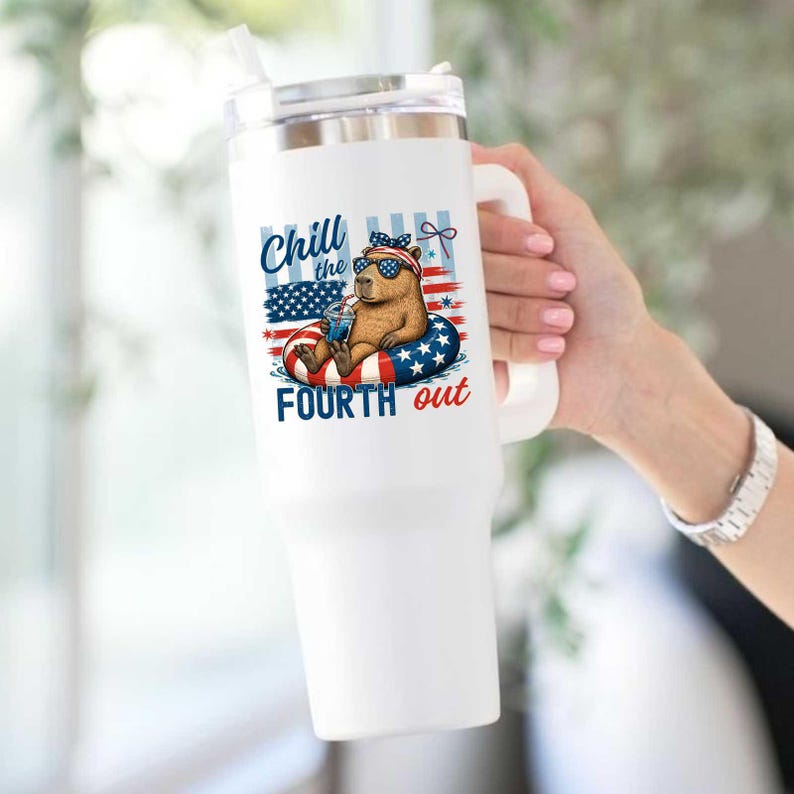 May include: White insulated tumbler with a handle, featuring a graphic of a capybara wearing sunglasses and a patriotic headband, floating on a red, white, and blue inner tube. The text "Chill the Fourth out" is displayed on the tumbler.