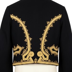 May include: Black jacket with gold embroidery. The jacket features ornate gold floral embroidery along the edges and back, creating a striking contrast against the dark fabric. The design includes intricate patterns and shapes.