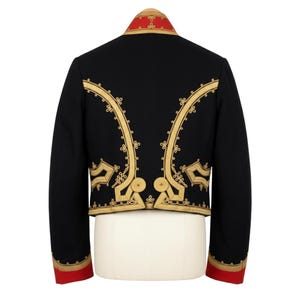 May include: Black jacket with gold embroidery and red accents. The jacket features ornate gold designs along the front and back, with red trim on the collar and cuffs. The jacket is displayed on a white mannequin.