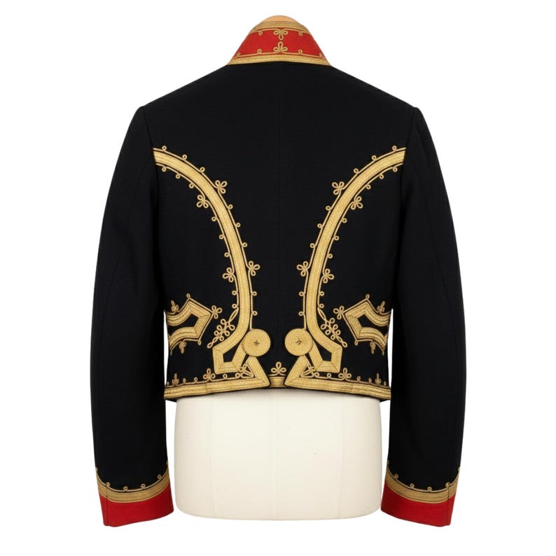 May include: Black jacket with gold embroidery and red accents. The jacket features ornate gold designs along the front and back, with red trim on the collar and cuffs. The jacket is displayed on a white mannequin.