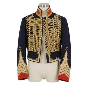 May include: A navy blue military-style jacket with gold rope detailing and gold buttons. The jacket features a red collar and red cuffs. The sleeves have gold chevron accents. The jacket is displayed on a mannequin.