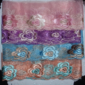 May include: Four different trims of embroidered lace with floral designs. The trims are pink, purple, blue, and peach.
