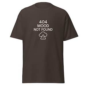 Könnte beinhalten: Braunes T-Shirt mit dem weißen Text "404 MOOD NOT FOUND" und einem Wolkensymbol mit Ausrufezeichen. Das T-Shirt hat kurze Ärmel und einen Rundhalsausschnitt.