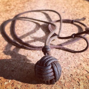 May include: A brown leather necklace with a knotted ball pendant.